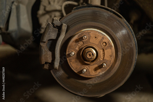 Close-up of a brake disc and pad on a car. Repairing and changing brakes on a car in a garage. A man repairs the brakes on his car himself. Brake repair concept.