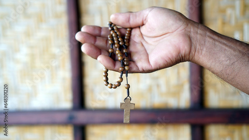Fotografia Person holding a wooden rosary in background with light