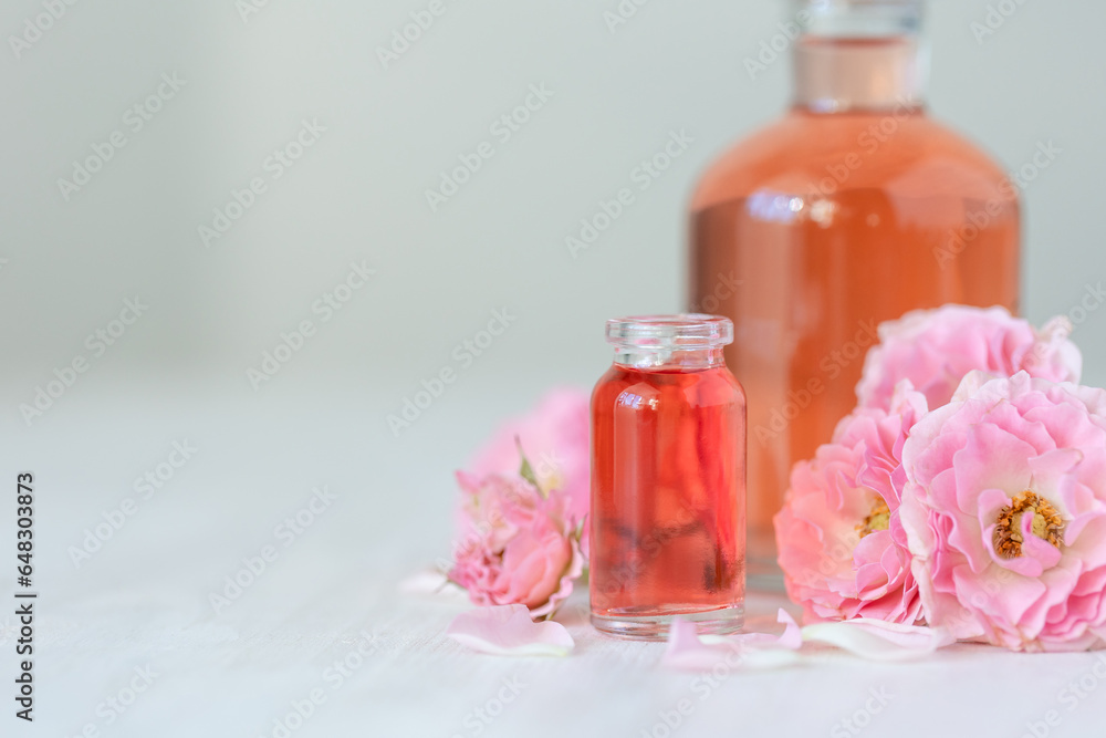 Concept of perfume with pure natural organic rose ingredient, essential oils. Glass bottles with flower herbal extract and elixir. Perfumery cosmetic toilet water fragrance, cream, skin care product Concept of perfume with pure natural organic rose ingredient, essential oils. Glass bottles with flower herbal extract and elixir. Perfumery cosmetic toilet water fragrance, cream, skin care product