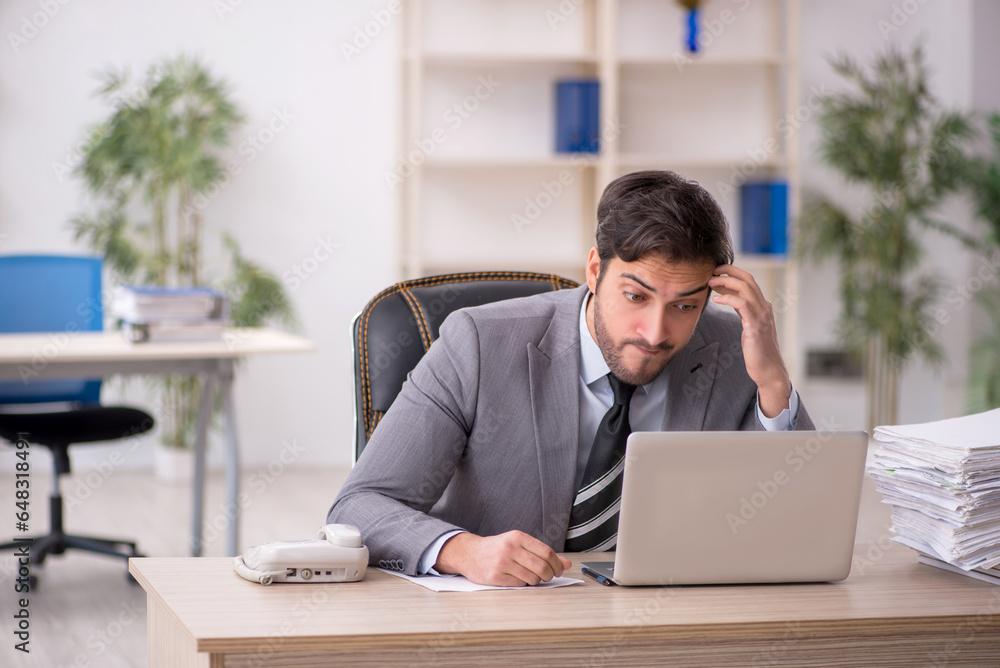 Young male employee and too much work in the office Young male employee and too much work in the office