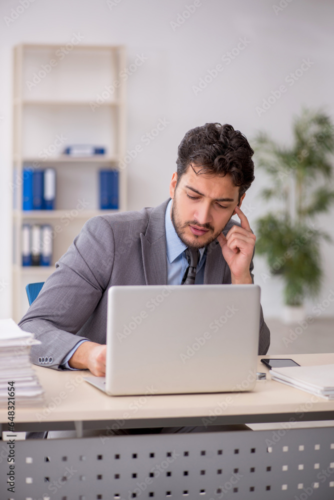 Young male employee and too much work in the office Young male employee and too much work in the office
