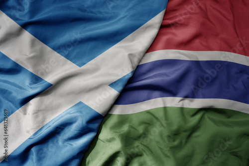 big waving national colorful flag of scotland and national flag of gambia .