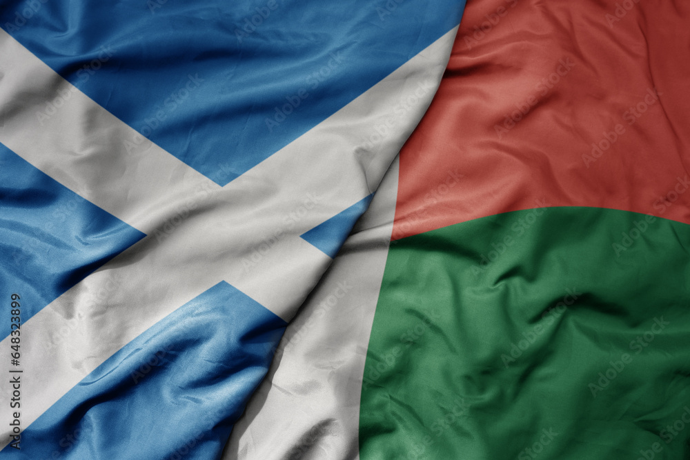 big waving national colorful flag of scotland and national flag of madagascar .