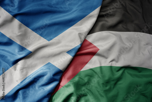 big waving national colorful flag of scotland and national flag of palestine .
