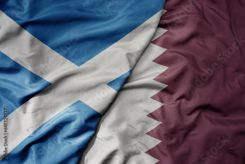 big waving national colorful flag of scotland and national flag of qatar .