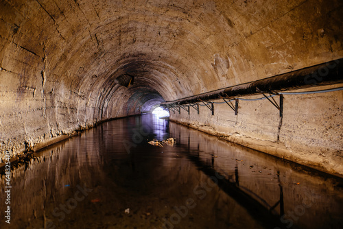 Underground flooded vaulted urban sewer tunnel with dirty sewage