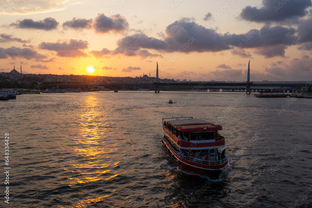 Fototapeta premium Tourist boat in front of Istanbul cityscape on sunset