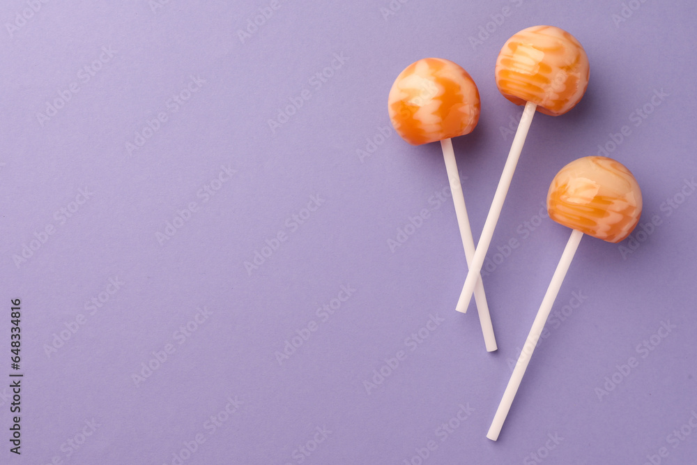 Tasty lollipops on violet background, flat lay. Space for text Tasty lollipops on violet background, flat lay. Space for text