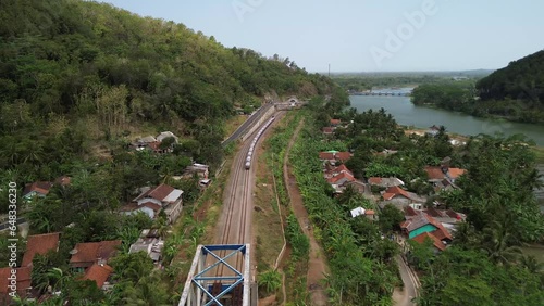 Train passing through railway bridge over  Serayu river with green forest background photo