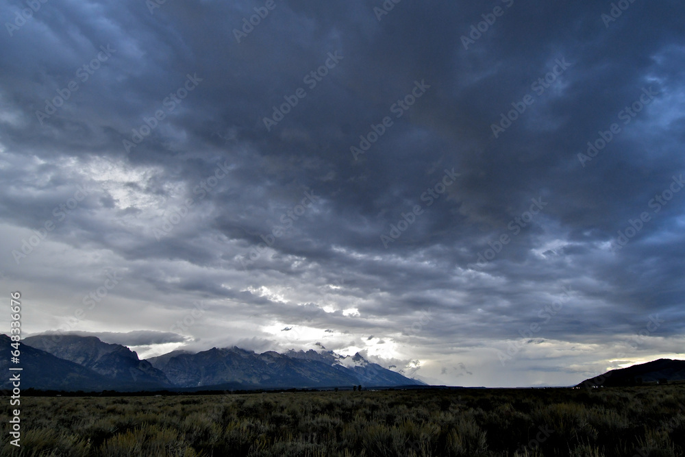 View up Snake River Valley with darkening skies and rain in the distance. Storm clouds shroud the Tetons, Wyoming 
