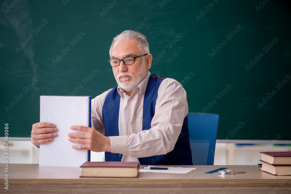 Old male teacher in front of green board Old male teacher in front of green board