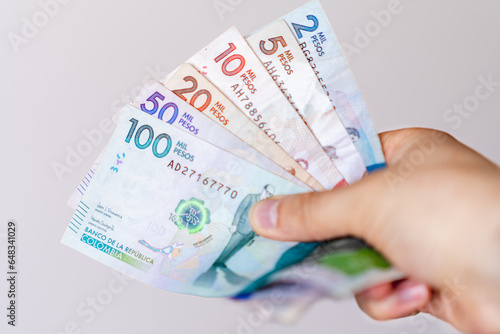 Photograph of Hand holding different Colombian banknotes of different denominations