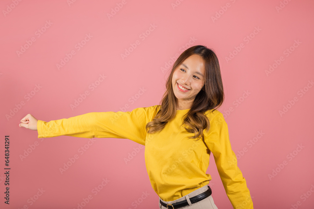 Asian young woman dancing with inspired face expression and raising hands up, Portrait of happy female model jocund in sneakers dancing, studio shot isolated on pink background, Time to relax Asian young woman dancing with inspired face expression and raising hands up, Portrait of happy female model jocund in sneakers dancing, studio shot isolated on pink background, Time to relax