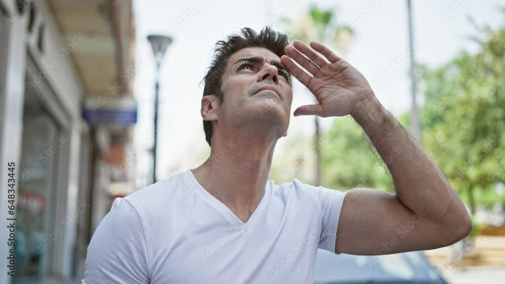 Young hispanic man looking to the sky with serious expression at street Young hispanic man looking to the sky with serious expression at street