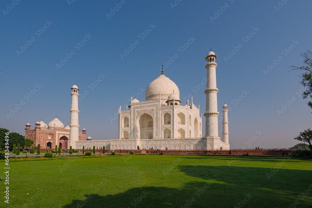 Taj Mahal historical monument at Agra India with clear blue sky and sprawling garden. An example of Mughal Indian architecture built on the Yamuna river banks.