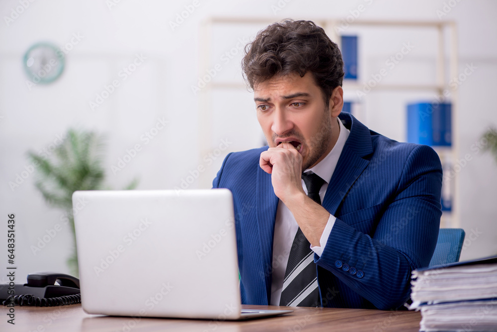 Young male employee and too much work in the office Young male employee and too much work in the office