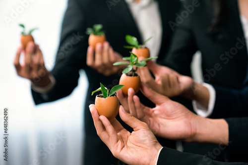 Eco-friendly investment on reforestation by group of business people holding sprout in egg shell together promoting CO2 reduction and natural preservation to save Earth with sustainable future. Quaint © Summit Art Creations
