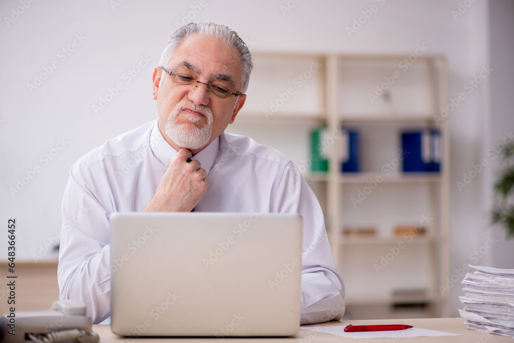 Old male employee working in the office Old male employee working in the office