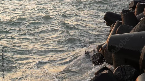 Calm summer evening waves splashing against the pier rocks at the Baltic sea in Ventspils