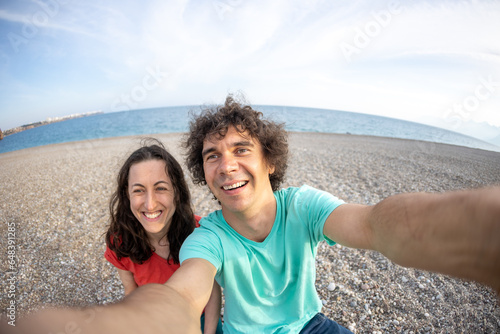 A man and a woman take a selfie on the seashore