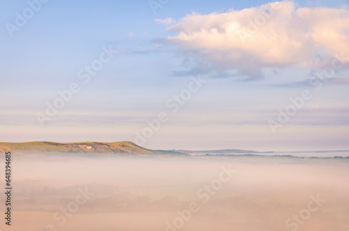 Misty morning sunrise from Wilmington Hill on the south downs east Sussex south east England UK