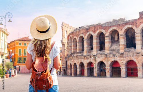 Traveler girl with hat and bag looking at Verona Arena,  tour tourism, travel,vacation in Italy- travel in Europe