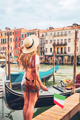 Female tourist holding italian flag traveling in Italy- Venice city, canal and traditional gondola