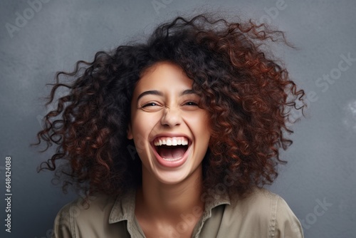 Beautiful stylish woman in casual outfit laughing and smiling white teeth, standing against grey background, studio background