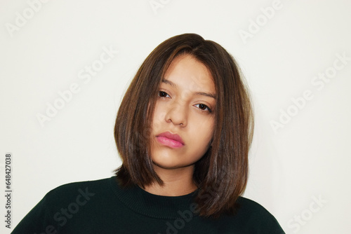 Retrato juvenil sobre fondo blanco. Mujer bonita con una mirada seria hacia la cámara.