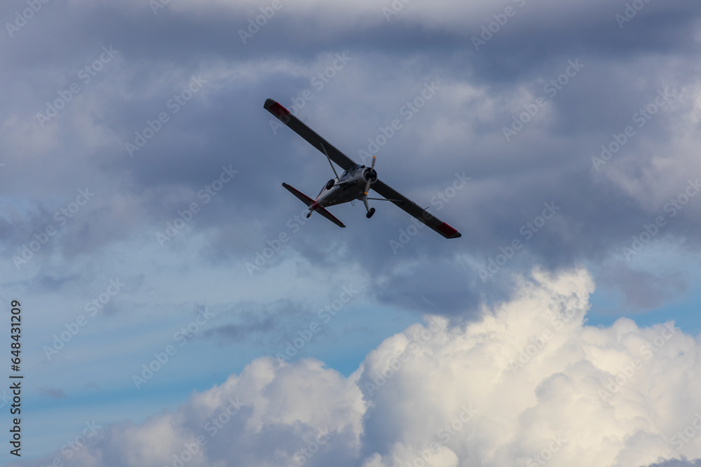 Fototapeta premium Plane flying on cloudy sky from side. Aviation background