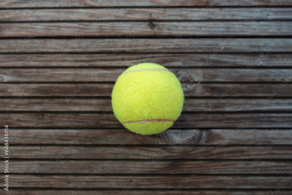 a tennis ball lying on wooden parquet