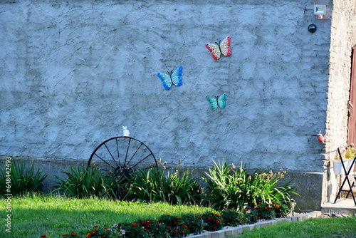 A view of a wall of an old abandoned shack, shelter, or house decorated with plastic butterflies, cart wheel and other items seen on a sunny summer day on a Polish countryside