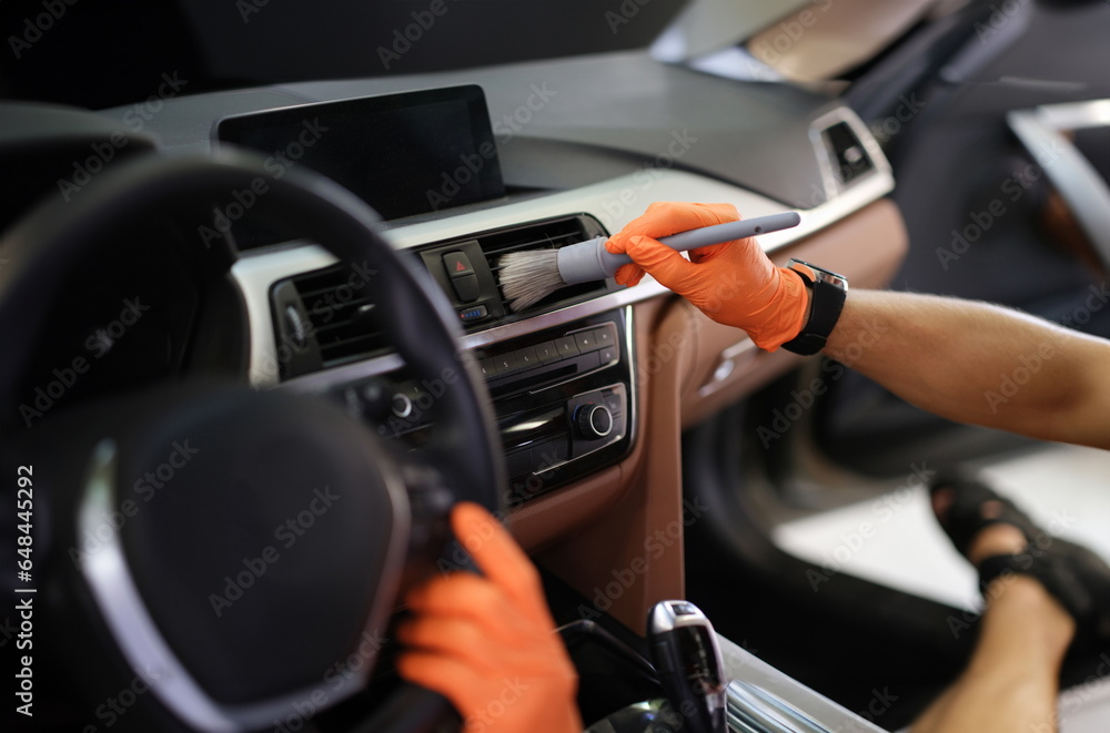 Male hand hold grey blush in orange protective gloves. Detailing car dry wash concept