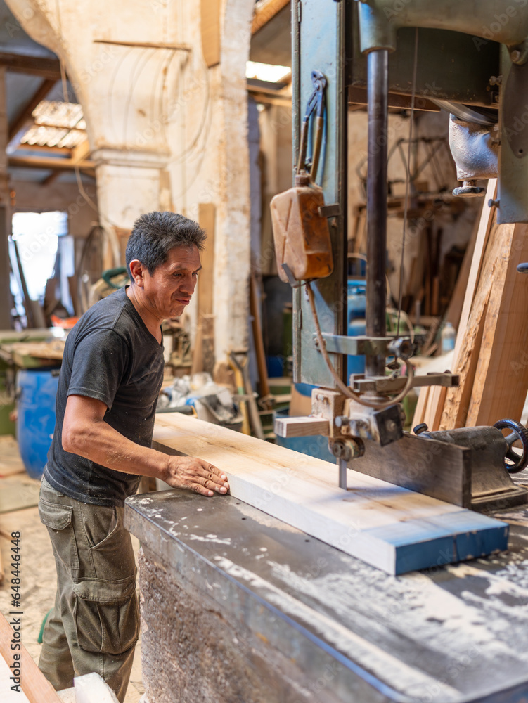 Experienced South American carpenter cutting a board with a saw - Elderly woodworking worker - Traditional carpentry - vertical photo Experienced South American carpenter cutting a board with a saw - Elderly woodworking worker - Traditional carpentry - vertical photo