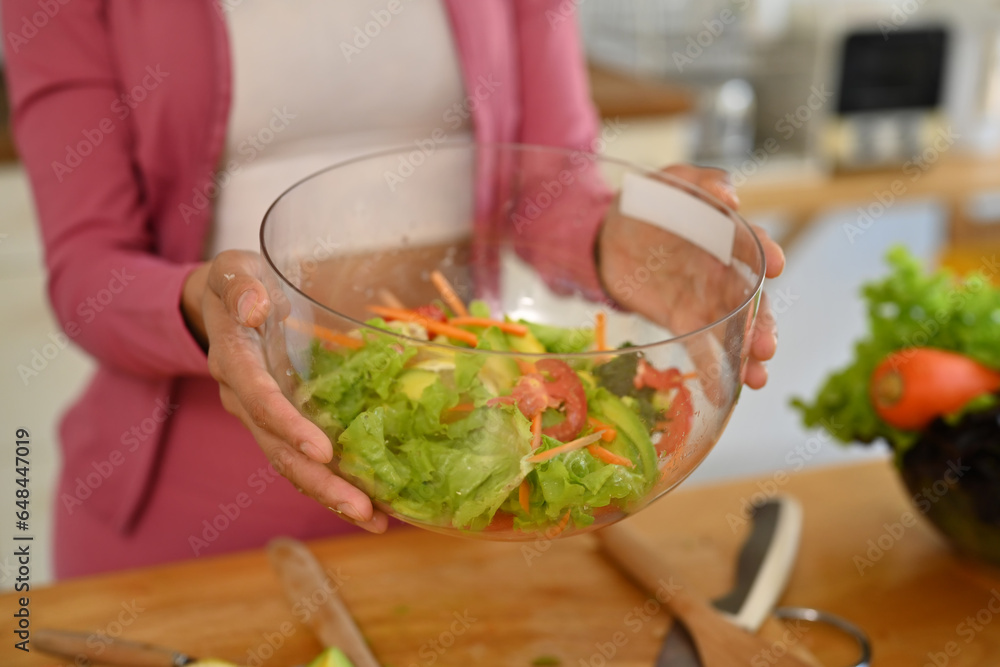 Young woman holding glass bowl of vegetable salad. Dieting, weight loss and healthy lifestyle concept Young woman holding glass bowl of vegetable salad. Dieting, weight loss and healthy lifestyle concept