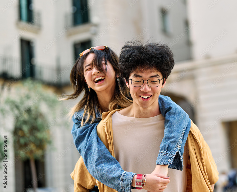 Fototapeta premium woman couple man happy hugging love young together piggyback travel tourist romantic hugging outside city vacation student smile fun relationship joy bonding