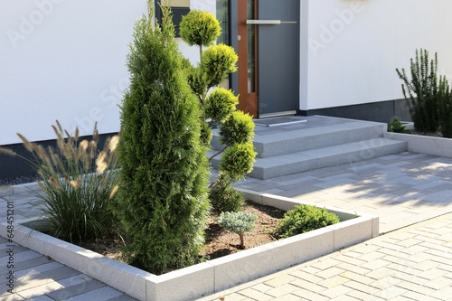 Wohnhaus mit schön und modern gepflastertem Vorgarten und schöner Bepflanzung photo