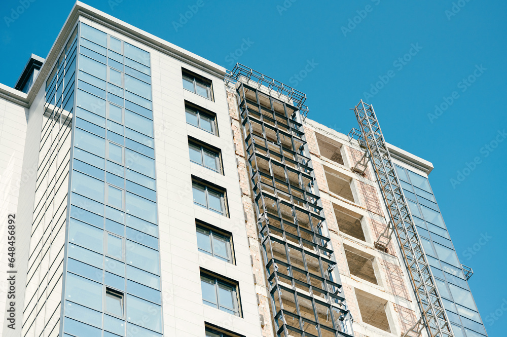 Low angle shot of a modern building in construction with blue sky as background. Low angle shot of a modern building in construction with blue sky as background.
