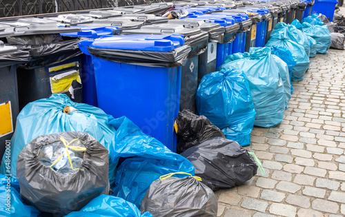Garbage on the streets of the city. Plastic containers for garbage. Garbage sorting. Black and blue garbage bags