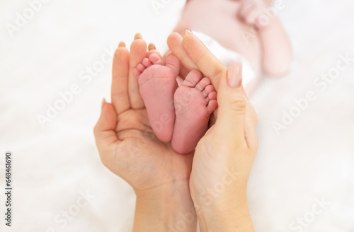 A parent holds the feet of a newborn baby in his hands.