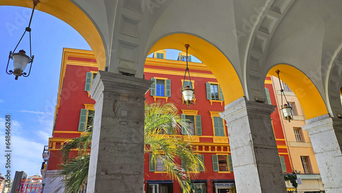 Architectural elements, red buildings, curves and arches of the city. Place Massena, during the day. Nice city, France