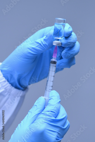 Nurse hand in medical glove holding syringe covid-19 coronavirus vaccine liquid from bottle preparing injection coronavirus influenza vaccine vaccination concept.