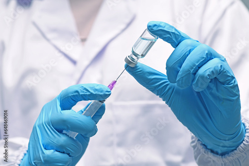 Nurse hand in medical glove holding syringe covid-19 coronavirus vaccine liquid from bottle preparing injection coronavirus influenza vaccine vaccination concept.