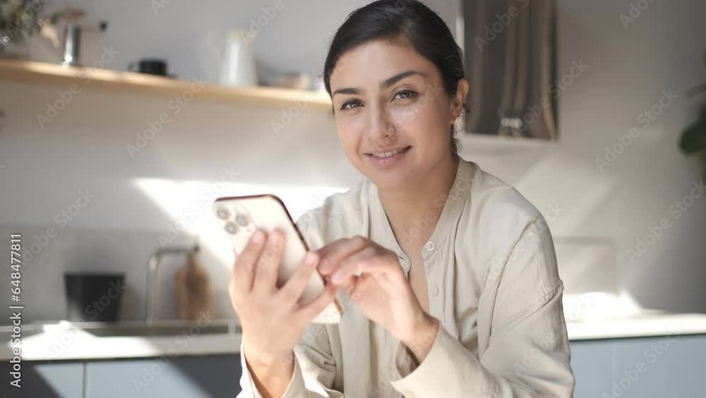 Happy woman smiling looking at camera. Home office interior. Business woman closeup portrait. Girl using smartphone internet surfing communication online. Pretty woman holding phone. Tapping, swiping Happy woman smiling looking at camera. Home office interior. Business woman closeup portrait. Girl using smartphone internet surfing communication online. Pretty woman holding phone. Tapping, swiping
