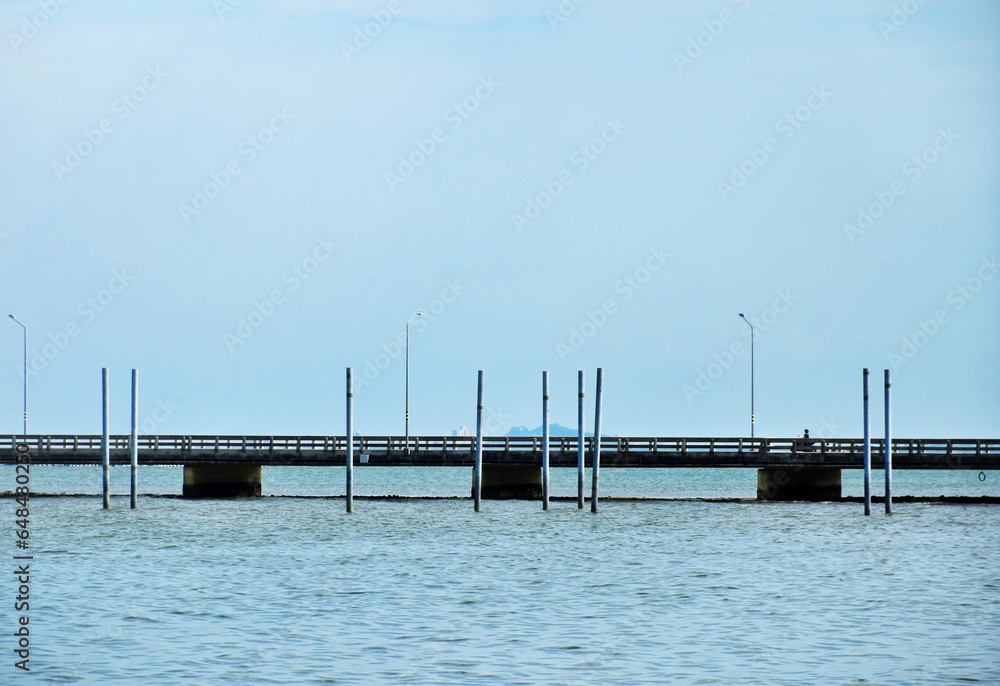 Obraz premium Bridge over the sea with motorcycles traveling on background of a clear sky and the sea waves, the beautiful gradient sky,traffic bridge.