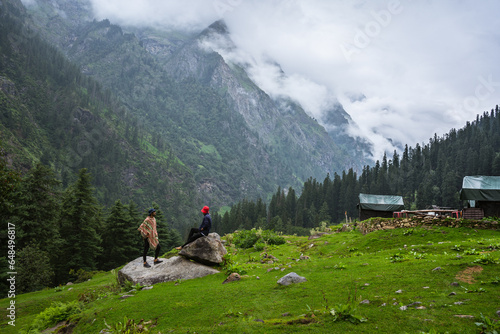 Young male hiker's with backpack relaxing on top of a mountain during Cloudy Weather - scenery from vacation - photo with space for your montage, Himachal Pradesh, Jibhi kheerganga, India.