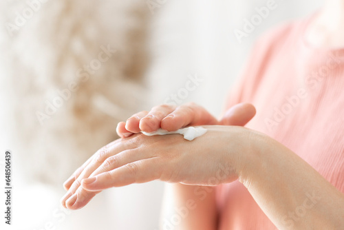 cold season hands skin protection. closeup woman applying protective cream on hands. 