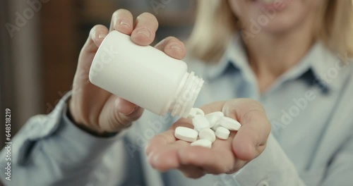 Female doctor holding pills in bottle at office