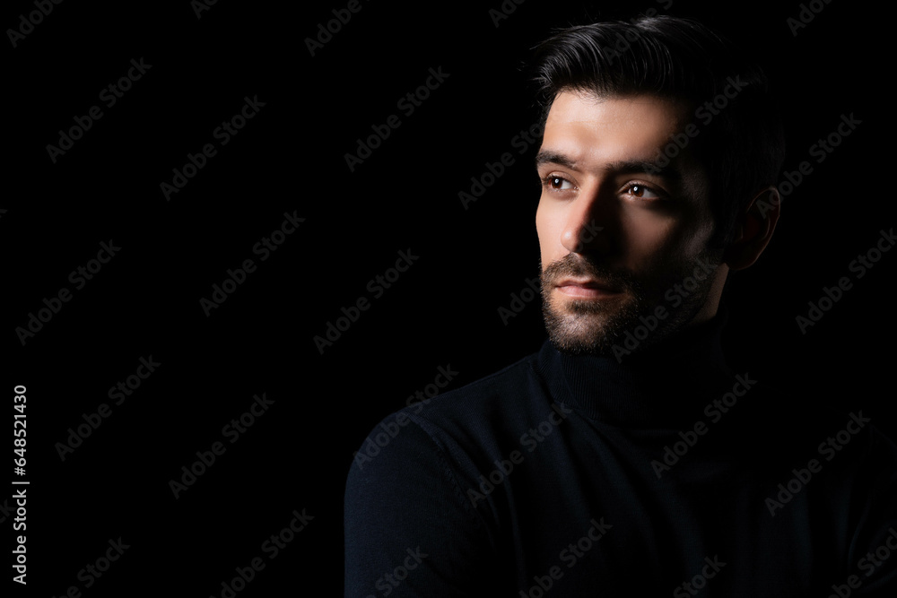 Pensive thinking handsome young beared man portrait Attractive bearded confident guy planning something looking at blank space Smart man thinking in the dark room Cool man look smart and good looking