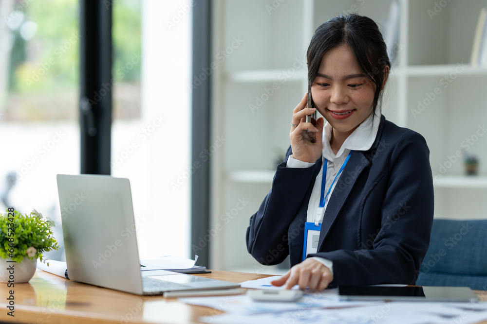 Asian businesswoman using mobile phone to communicate, chat, negotiate, search internet, news, email while working online on laptop computer at office. Asian businesswoman using mobile phone to communicate, chat, negotiate, search internet, news, email while working online on laptop computer at office.